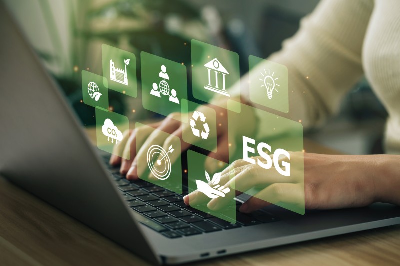 Hands typing on a laptop with ESG and sustainability icons, representing Pitman Training’s Sustainability in Business Course.